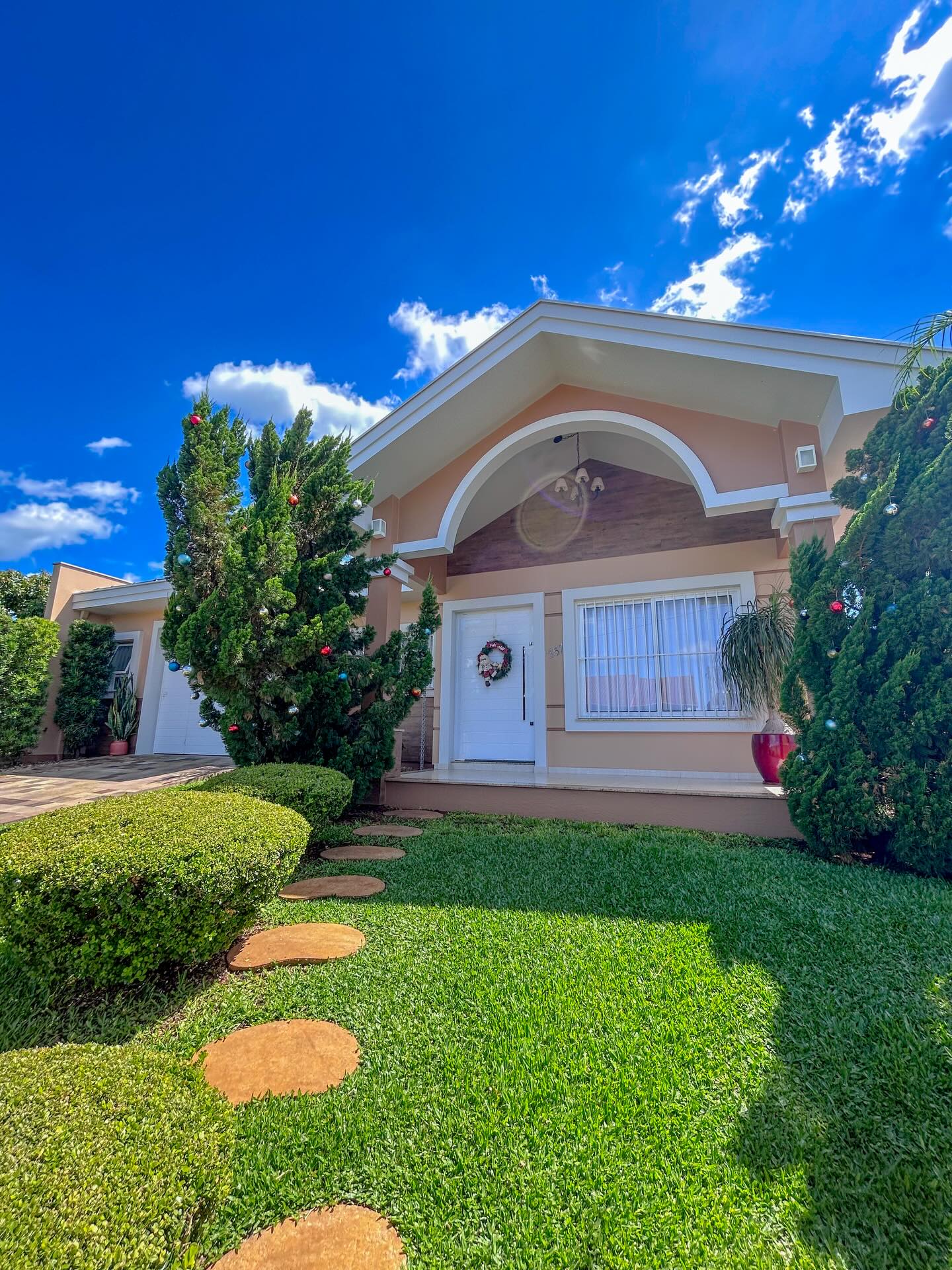 Residência com fachada em tom rosé e jardim
