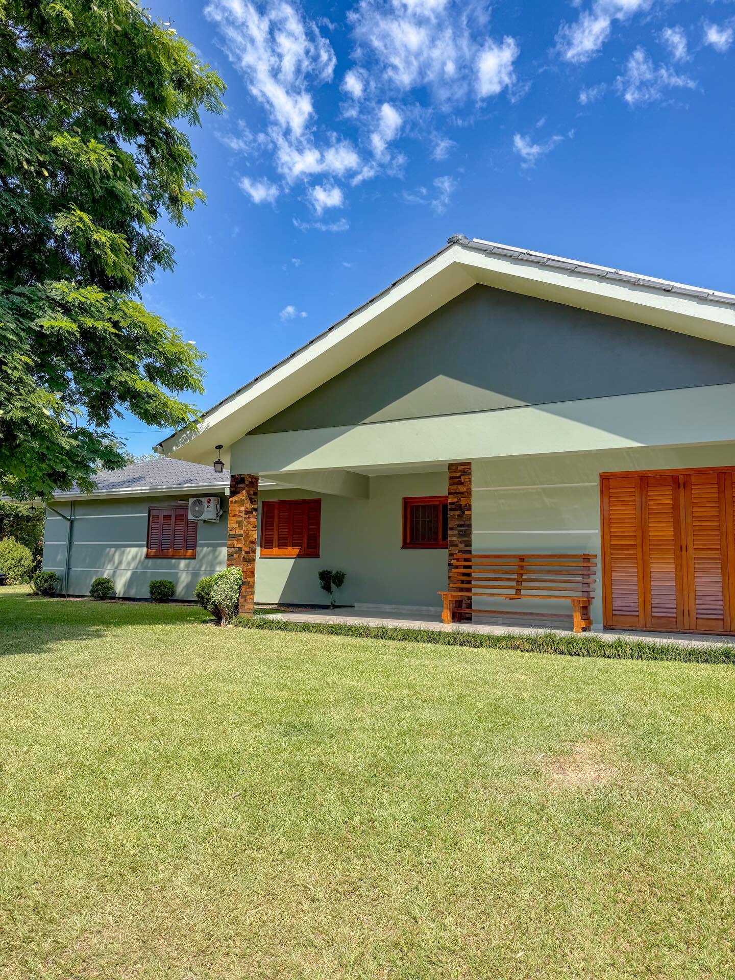 Casa com fachada em verde suave e esquadrias em madeira